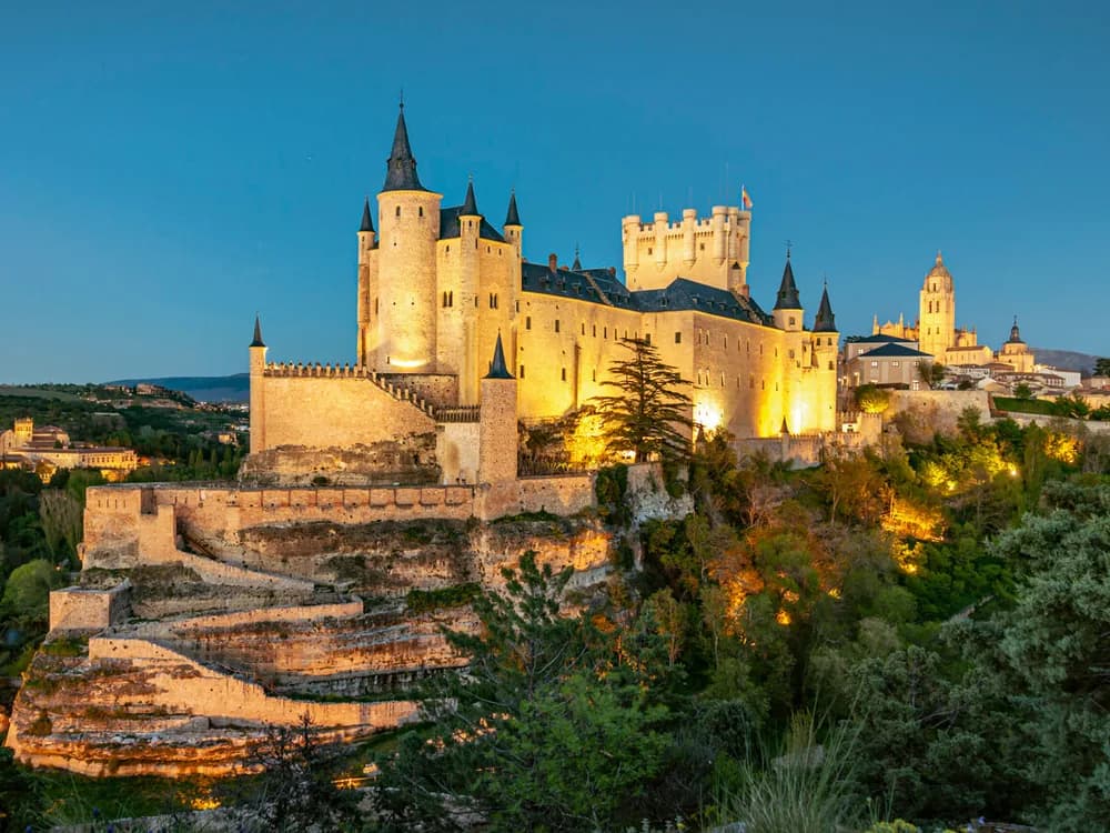 The Alcázar of Segovia on its rocky prow with the Castilian plain behind it at golden hour