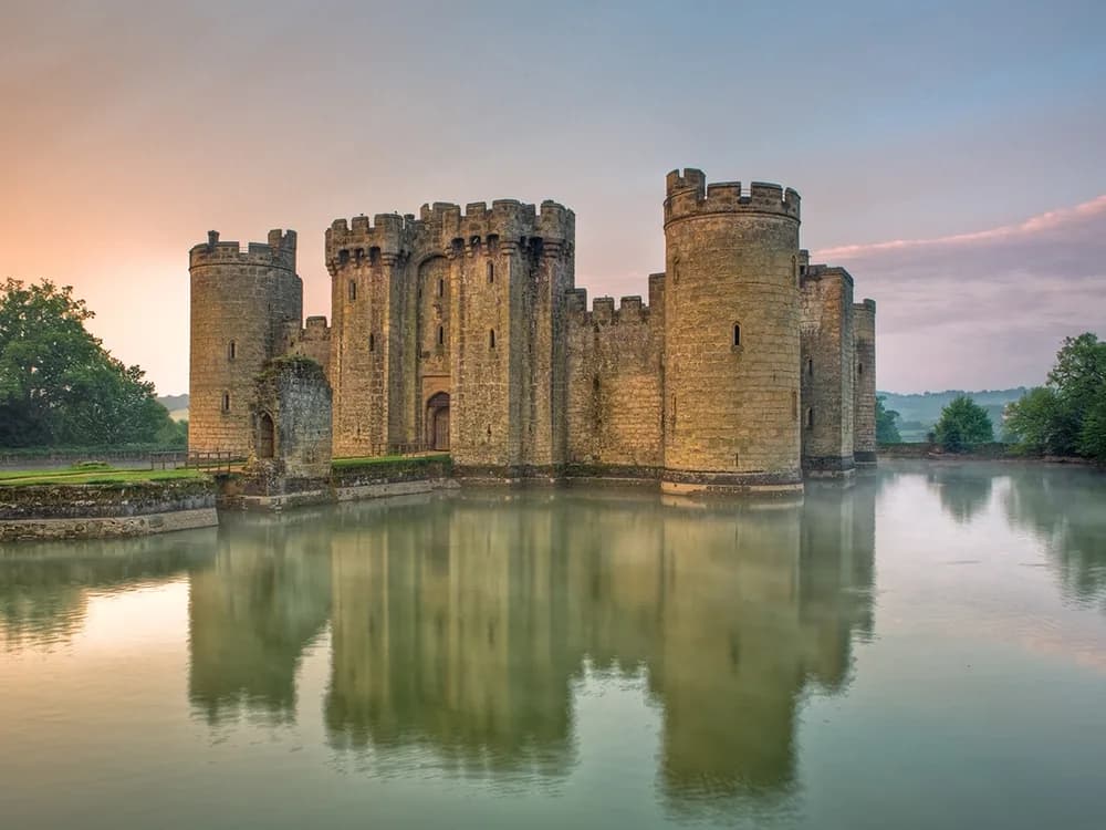 Bodiam Castle reflected in its moat on a still summer morning, water lilies surrounding the walls