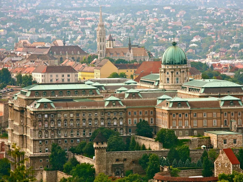Buda Castle and its green dome above the Danube at dusk, with the Chain Bridge illuminated