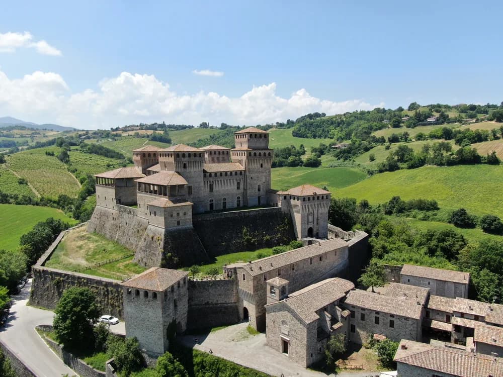 The Castle of Torrechiara's four towers and curtain wall rising above the Apennine foothills near Parma