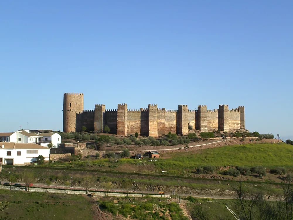 The semicircular towers and curtain wall of Baños de la Encina Castle above the olive groves of Jaén province