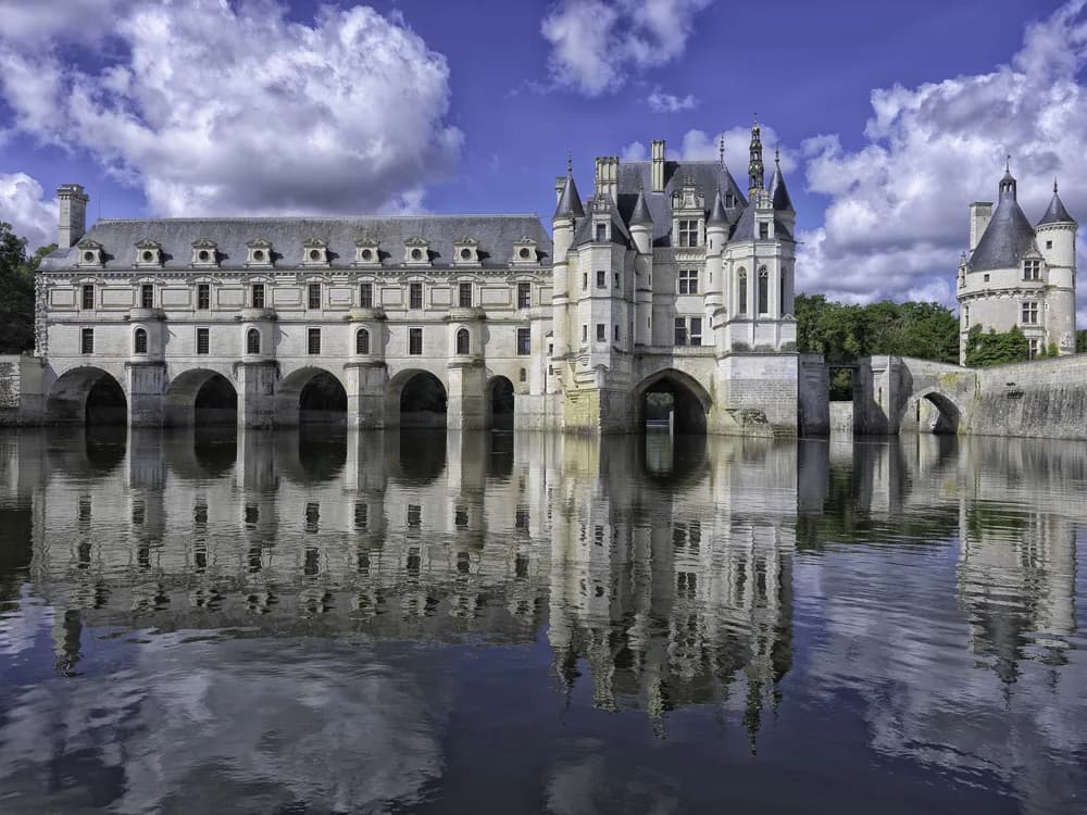 Château de Chenonceau spanning the Cher river on its five arches, reflected in still water at sunrise