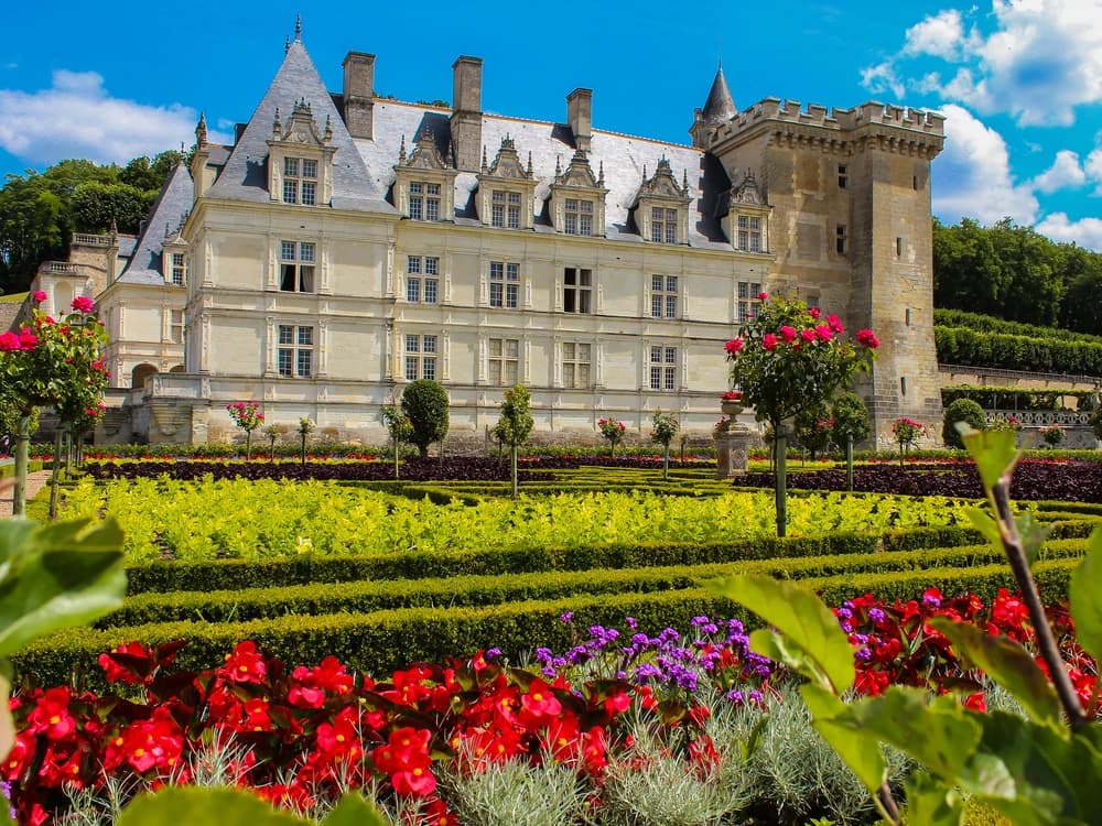 The geometric parterres of Château de Villandry's ornamental kitchen garden seen from the terrace above, with the Renaissance château in the background