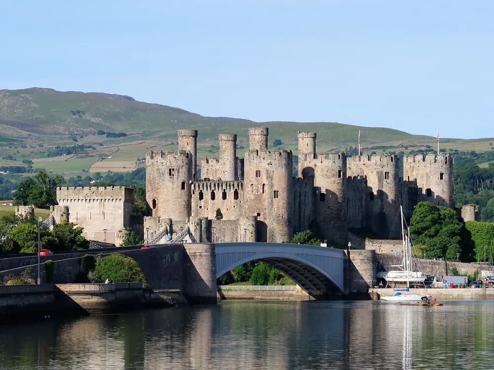 Conwy Castle and its eight towers reflected in the Conwy Estuary at dawn