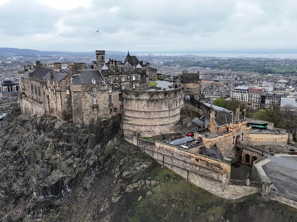 Edinburgh Castle on Castle Rock at dusk, lit against a dramatic purple sky above the city rooftops