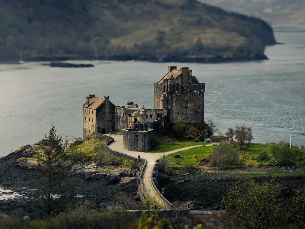 Eilean Donan Castle on its tidal island at the confluence of three Scottish sea lochs, reflected in the still water of Loch Duich