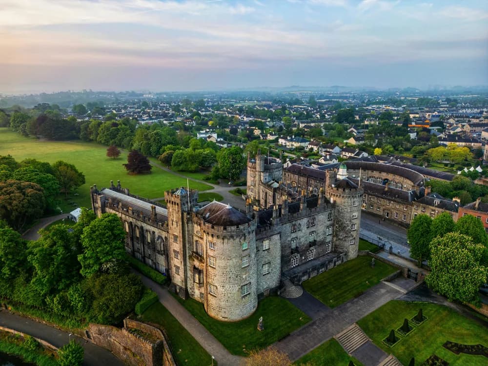 Kilkenny Castle above the River Nore with its three towers and parkland in early morning light