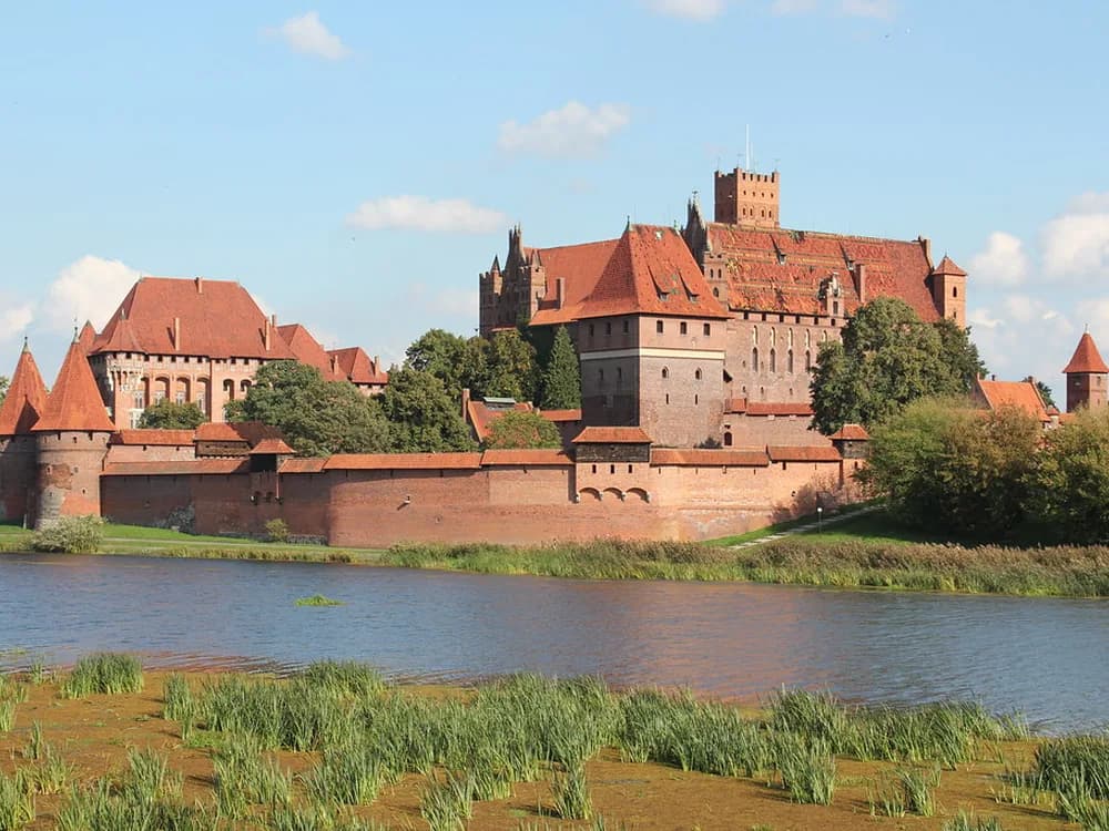 Malbork Castle's brick towers reflected in the Nogat River
