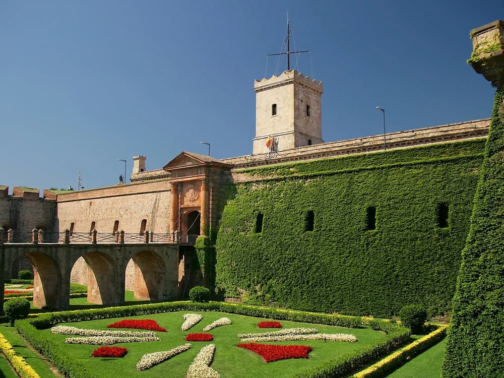 Montjuïc Castle's star-shaped bastions overlooking the port of Barcelona and the Mediterranean coast, with the city's skyline and distant hills beyond