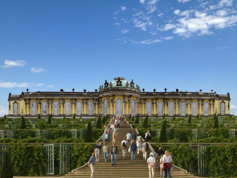 Sanssouci Palace's elegant single-storey Rococo facade seen from the terraced vineyard gardens, with the central fountain and formal parterre below in Potsdam