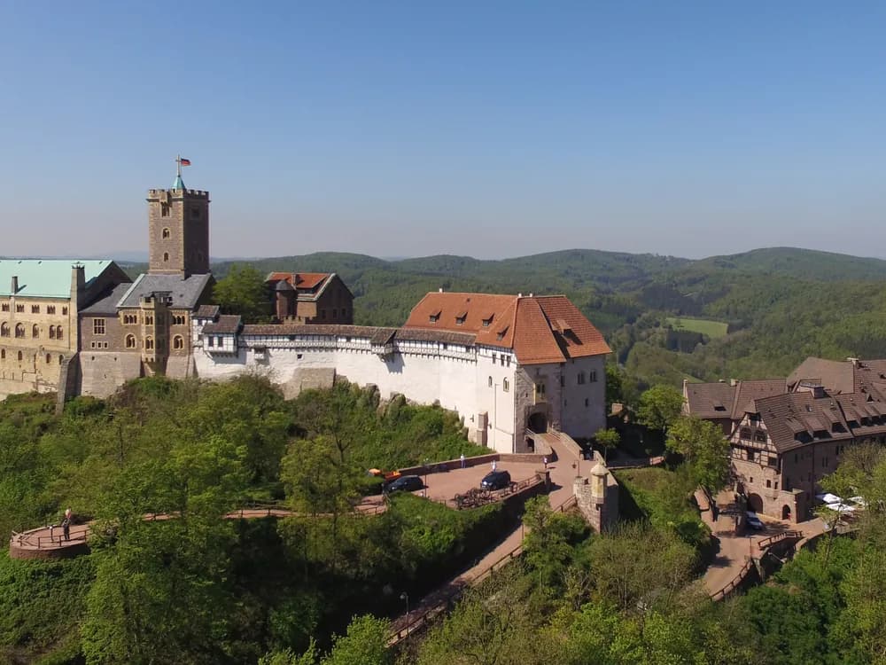 Wartburg Castle above the autumn forest of Thuringia, its red roofs visible above the beech trees