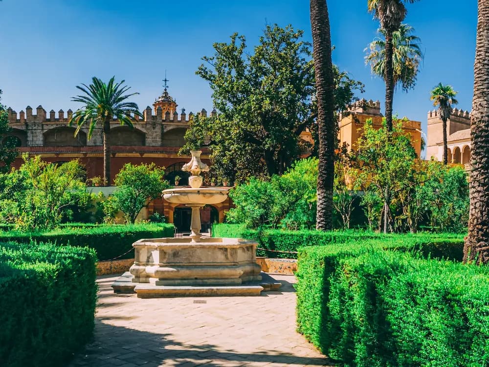 The Courtyard of the Maidens in the Royal Alcázar of Seville — Mudéjar arches reflected in the central pool