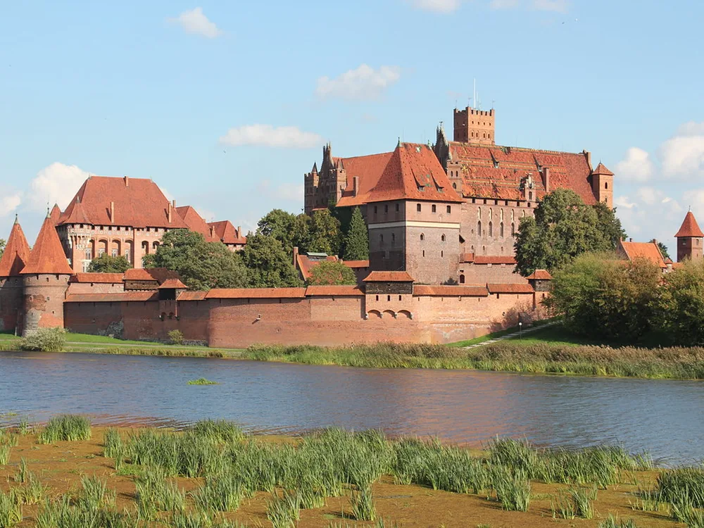 Malbork Castle's brick towers reflected in the Nogat River