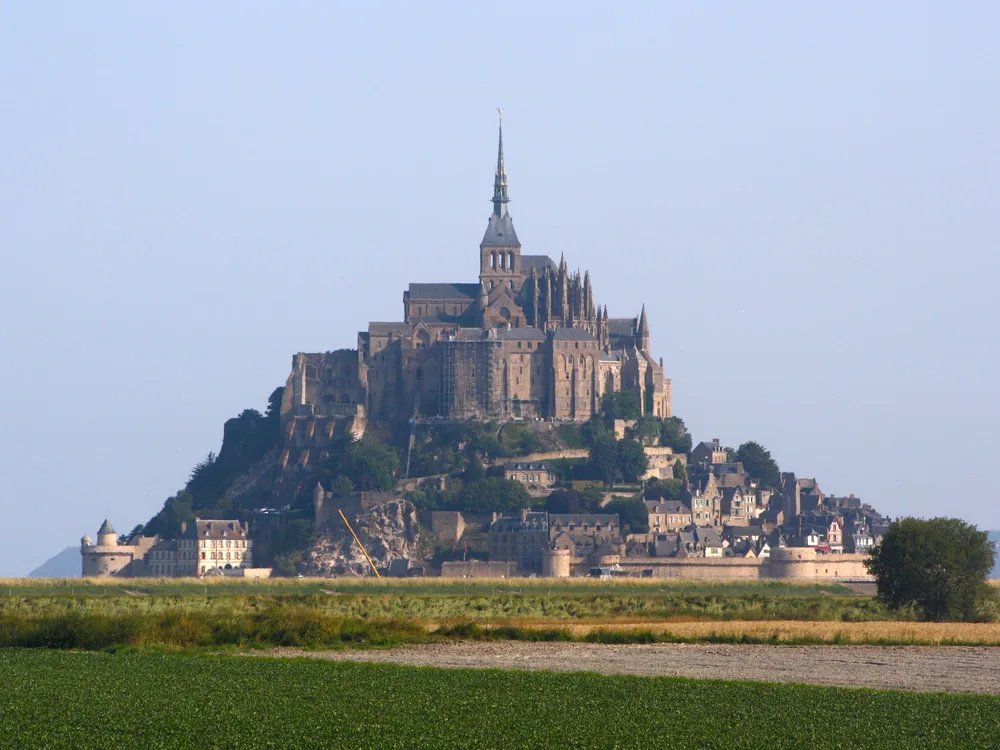 Mont-Saint-Michel rising from the tidal bay of Normandy at high tide, surrounded by sea at dawn